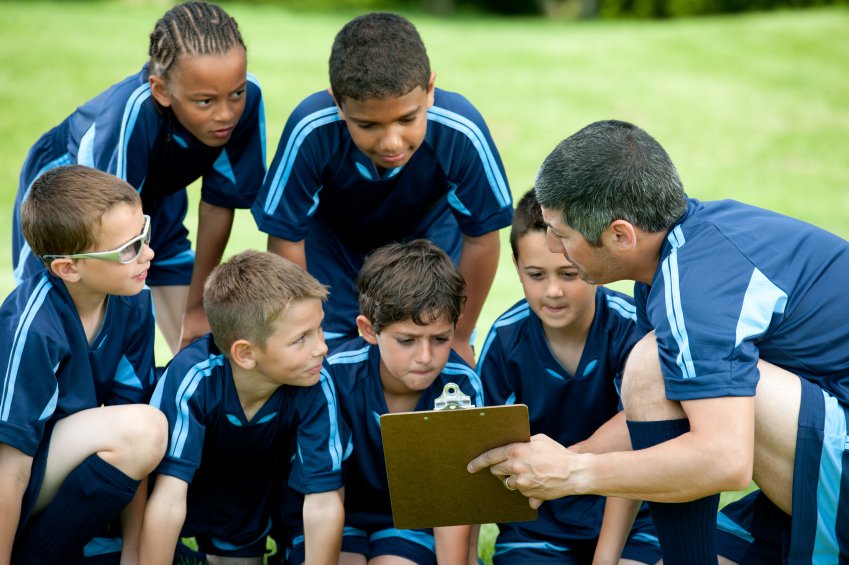 Youth football coach teaching his players